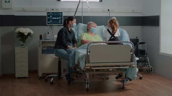 Niece Visiting Senior Patient with Face Mask in Hospital Ward alt