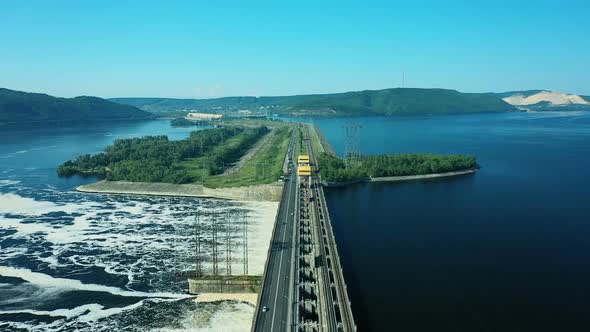 View From a Quadcopter To the Road Bridge Over the River Dam. Cars Go Over the Bridge Over the River