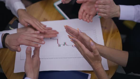 Top View Table with Business Graph and Hands of Colleagues Clapping in Slow Motion alt