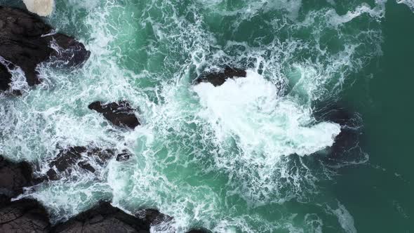 Aerial view of ocean waves splashing in the rocky beach alt