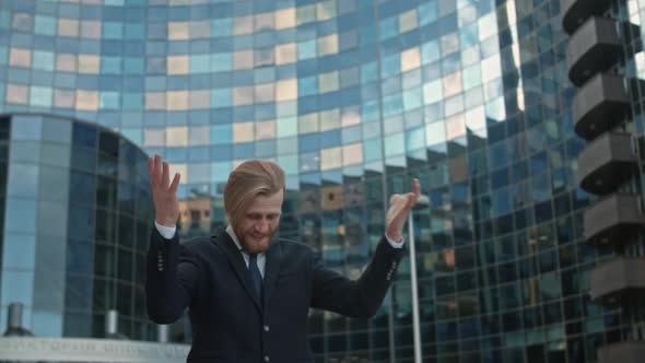 Positive Euphoric Young Businessman with Beard Dancing in Front the Office Center Mirrored Building