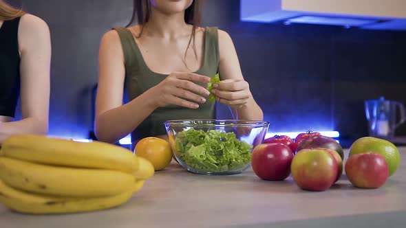 Smiling Young Woman Eating Lettuce Leaves During Preparing with Her Girlfriend Vegetable Fresh Salad alt