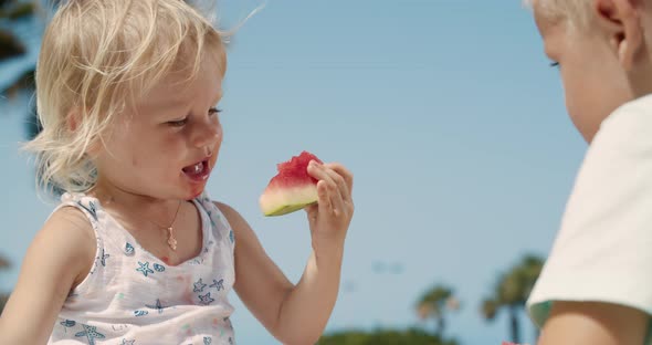 Beautiful Little Girl Bites a Slice of Watermelon on a Clear Sunny Day