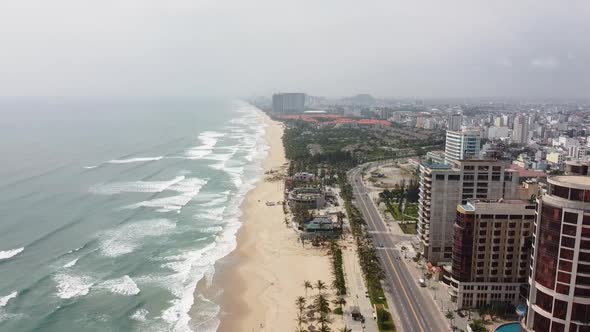 Aerial View of a Beautiful and Tranquil City with Big Buildings and Long White Sand Beach alt