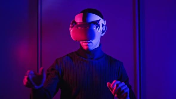 Young Man in a VR Helmet Interacts with Virtual Reality and 360 Media Content alt