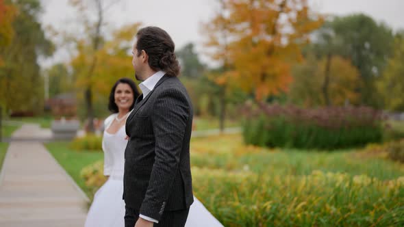 the Bride and Groom Hold Hands Laugh and Dance in the Autumn Park alt