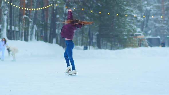 Lady with Long Hair Spins on Outdoor Ice Rink in Evening