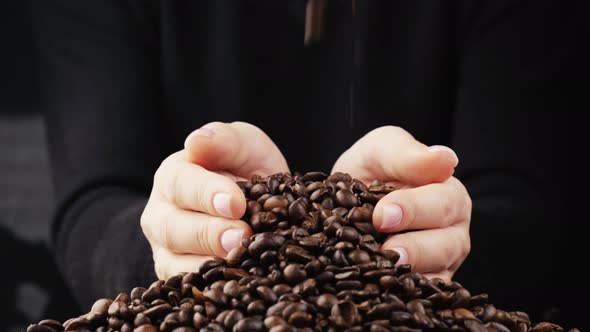 He Picks Up the Dark Coffee Beans in His Hands and Pours Them Down on the Table