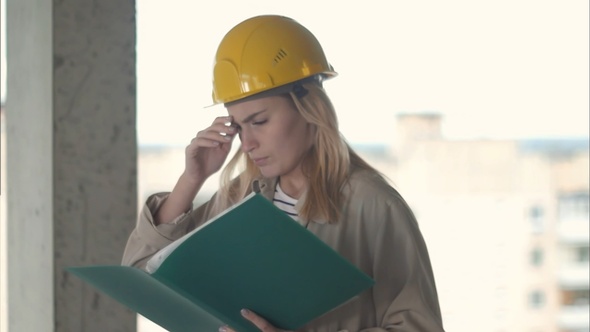Unsatisfied young engineer woman standing with plan documents