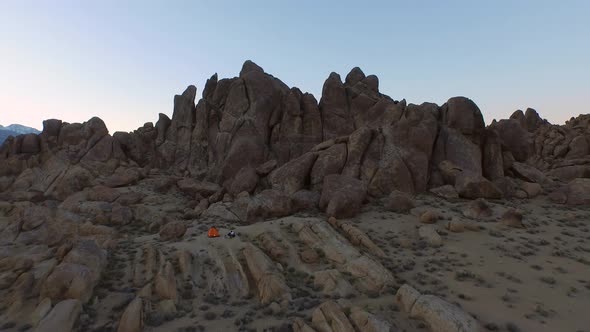 Aerial shot of a young man backpacker camping with his dog in a mountainous desert. alt