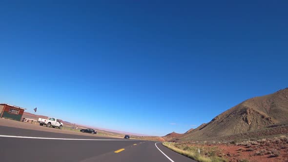 A car drives along a scenic road on a sunny day in California.