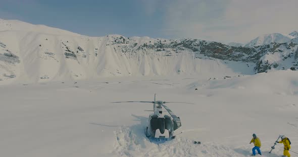 Aerial view The skiers go to the helicopter in the snowy mountains alt