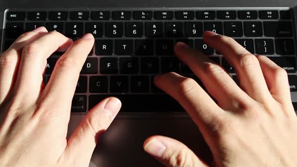 Static overhead shot of Caucasian person typing on a laptop keyboard on desk. alt