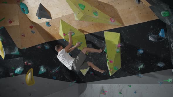 Handheld Young Climber Training on a Climbing Wall Practicing Rockclimbing and Moving Up alt