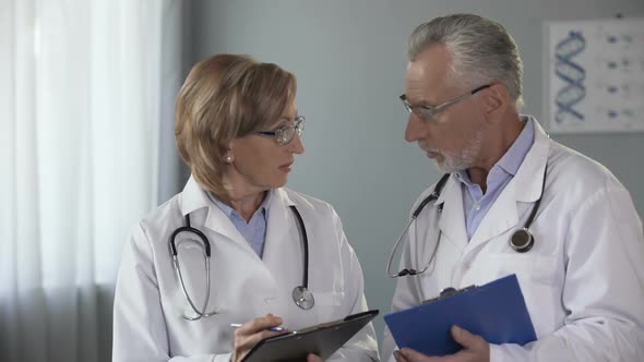 Experienced Male and Female Doctors Comparing Results, Consulting on Diagnosis alt