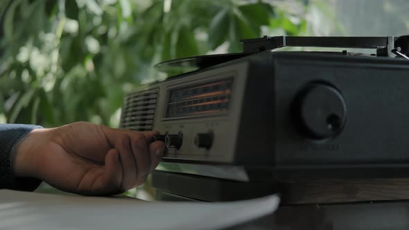 Male Hand Turns on Music on a Vintage Record Player for Vinyl Records.