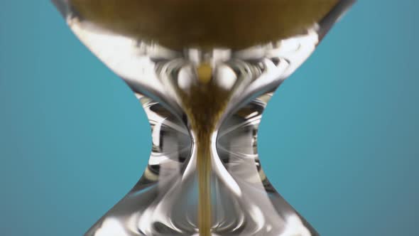 An Hourglass Made of Yellow Metal Shavings Passes Through a Funnel Symbolizing the Concept of Time