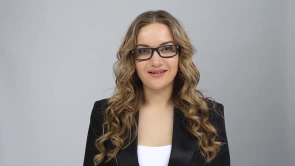Portrait of Girl in Bussines Suit Fixing Her Glasses and Raising Eyebrow Looking at Camera alt