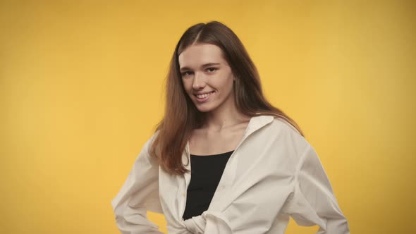 Young Adult Caucasian Woman is Turning and Shaking Her Hair on a Bright Yellow Background alt