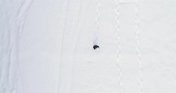 Overhead Aerial Top View Over Man Walking with Snowshoes on White Snow Covered Field in Winter