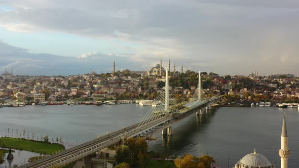 Aerial drone of a cloudy sunrise morning in Istanbul Turkey as seagulls fly across Halic Metro Bridg alt