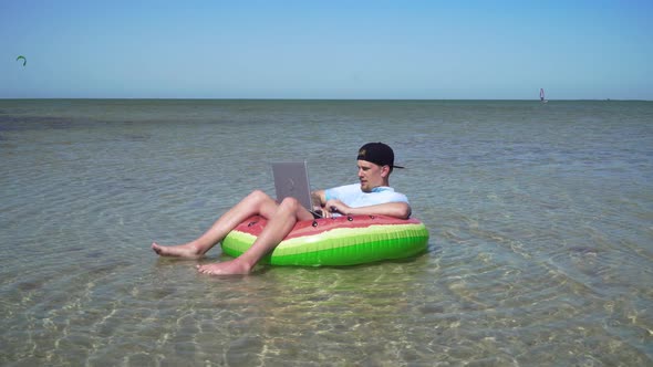 A Young Business Person Is Enthusiastically Working Behind a Laptop Swaying on the Waves of Sea alt