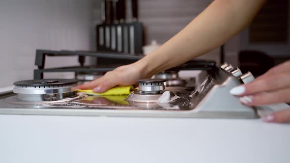 Hand cleaning stove. Close up of female hand cleaning the gas stove in kitchen alt