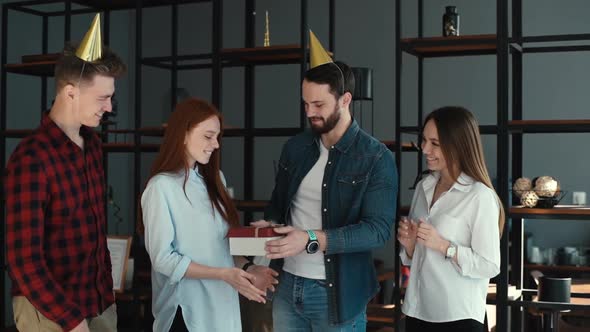 Happy Business Team of Office Employees Giving Gift or Presents To Young Female Coworker alt