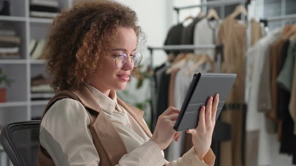 Young Female Entrepreneur in Glasses Uses Modern Technologies and Sells Clothes Online Using a alt