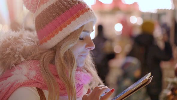 Woman in Snowy Night Using Digital Tablet in Winter City