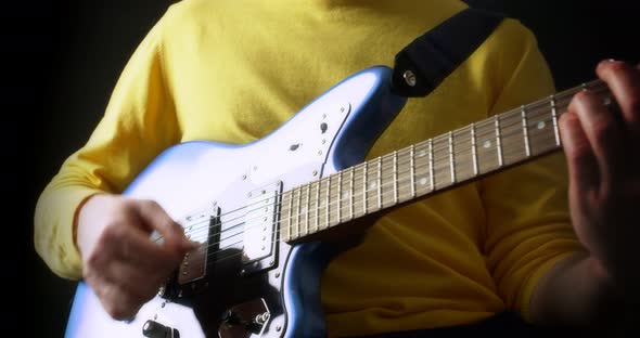 Male Guitarist in a Yellow Jumper Plays an Electric Guitar on Black Background