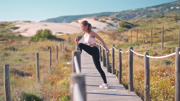 Flexible Caucasian Girl Stretches Legs After an Intensive Running Workout alt