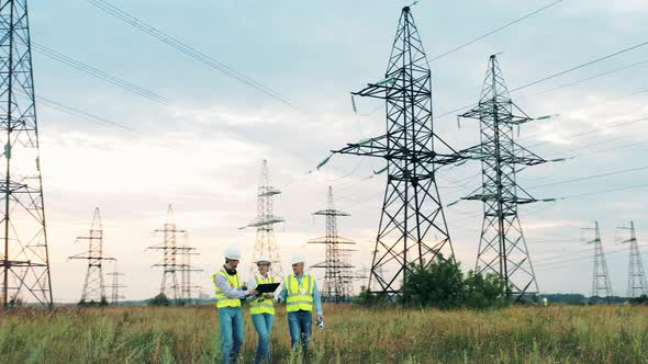 Energetics Specialists Are Walking Along the Area with Electrical Towers. Enenrgy Engineers alt