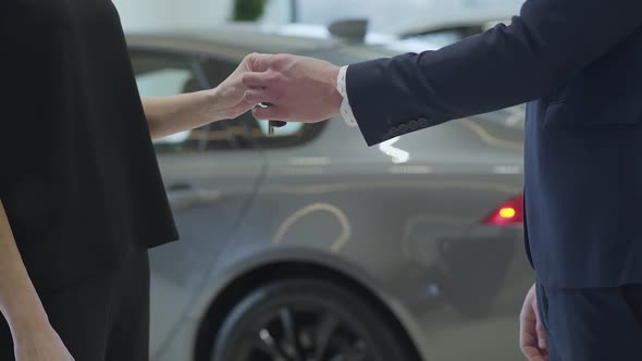 Unrecognized Confident Professional Salesman in a Business Suit Gives a Car Keys alt