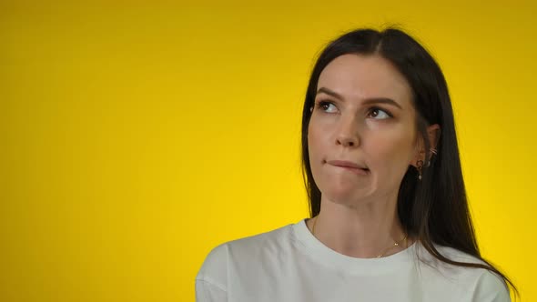Thoughtful Young Woman Looks Up Bites Her Lip and Thinks Deeply About Something alt