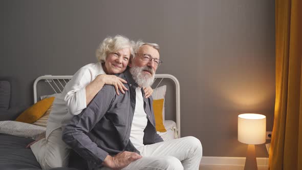 Portrait of Cheerful Senior Couple Relaxing at Home in Bedroom