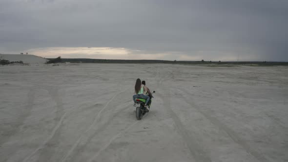 A Beautiful Young Couple Man and Woman are Riding on a Motorbike Together on the Beach During Sunset