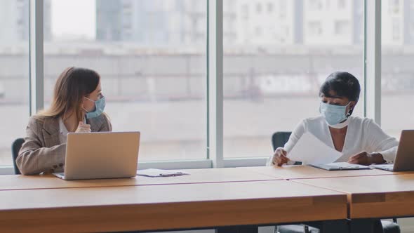 Two Multiracial Female Worker Caucasian Woman Manager and African Businesswoman Sitting in Office at alt