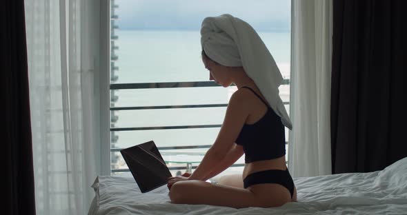 Attractive Woman Working on Computer in Internet and Looking Out the Window in Morning