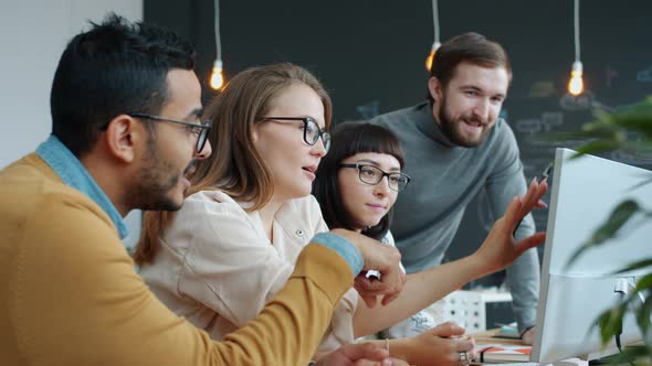 Slow Motion of Multi-ethnic Group of People Talking in Office Pointing at Computer Screen alt