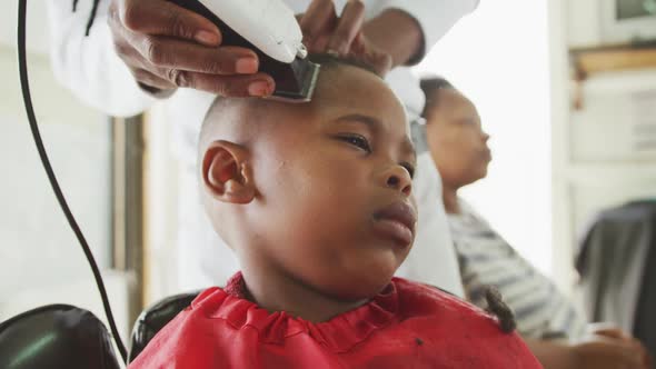 Close view of African man cutting African boy hair alt
