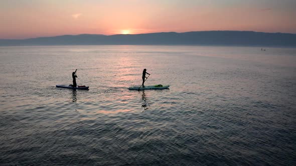 Stand Up Paddle Board Silhouette of Two Women on Water Slow Motion Aerial SUP