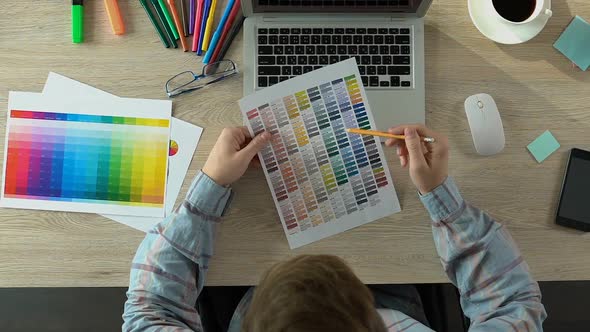 Decorator Choosing Color on Palette and Working on Laptop at Office, Top View alt