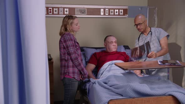 Doctor goes over x-ray with patient and his daughter