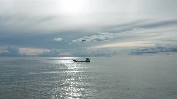 Helicopter hovering above barge to load goods in net hanging from cable, aerial alt