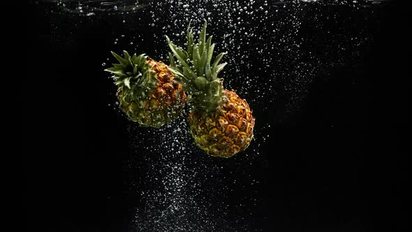 Tropical Fruits Pineapple Falling Into Water with Splash and Air Bubbles on Black Background alt