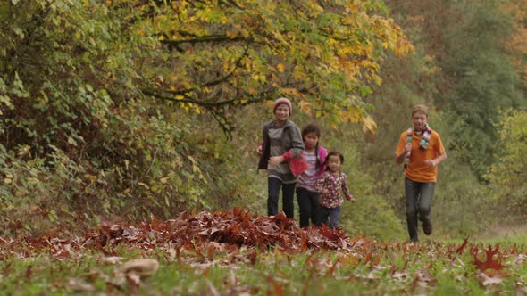 Group of kids in Fall running to pile of leaves