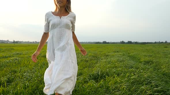 Beautiful Woman in White Dress Running on the Green Field, Wind Blowing Hair