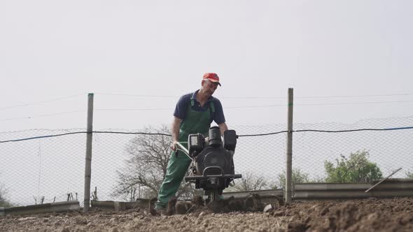 Man Plowing the Land in the Garden on Sky Background