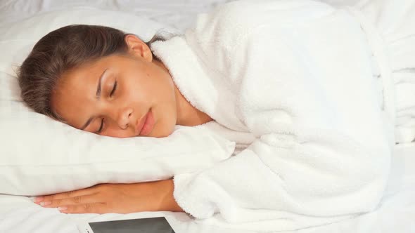 Beautiful Woman Waking Up To Turn Off Alarm Clock on Her Smart Phone alt